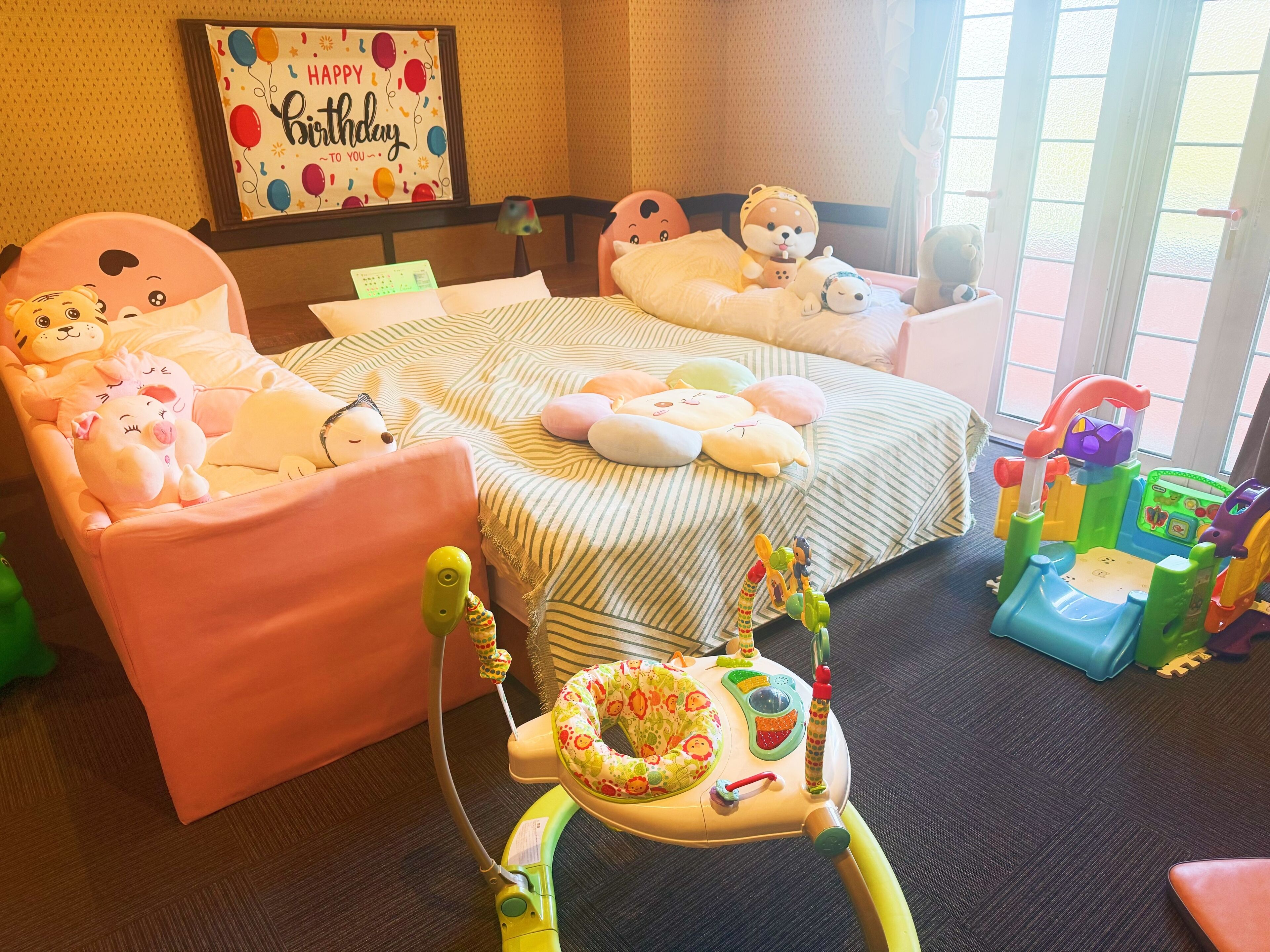 Een kinderkamer met een bed, twee stoelen, een speeltafeltje en een wieg.