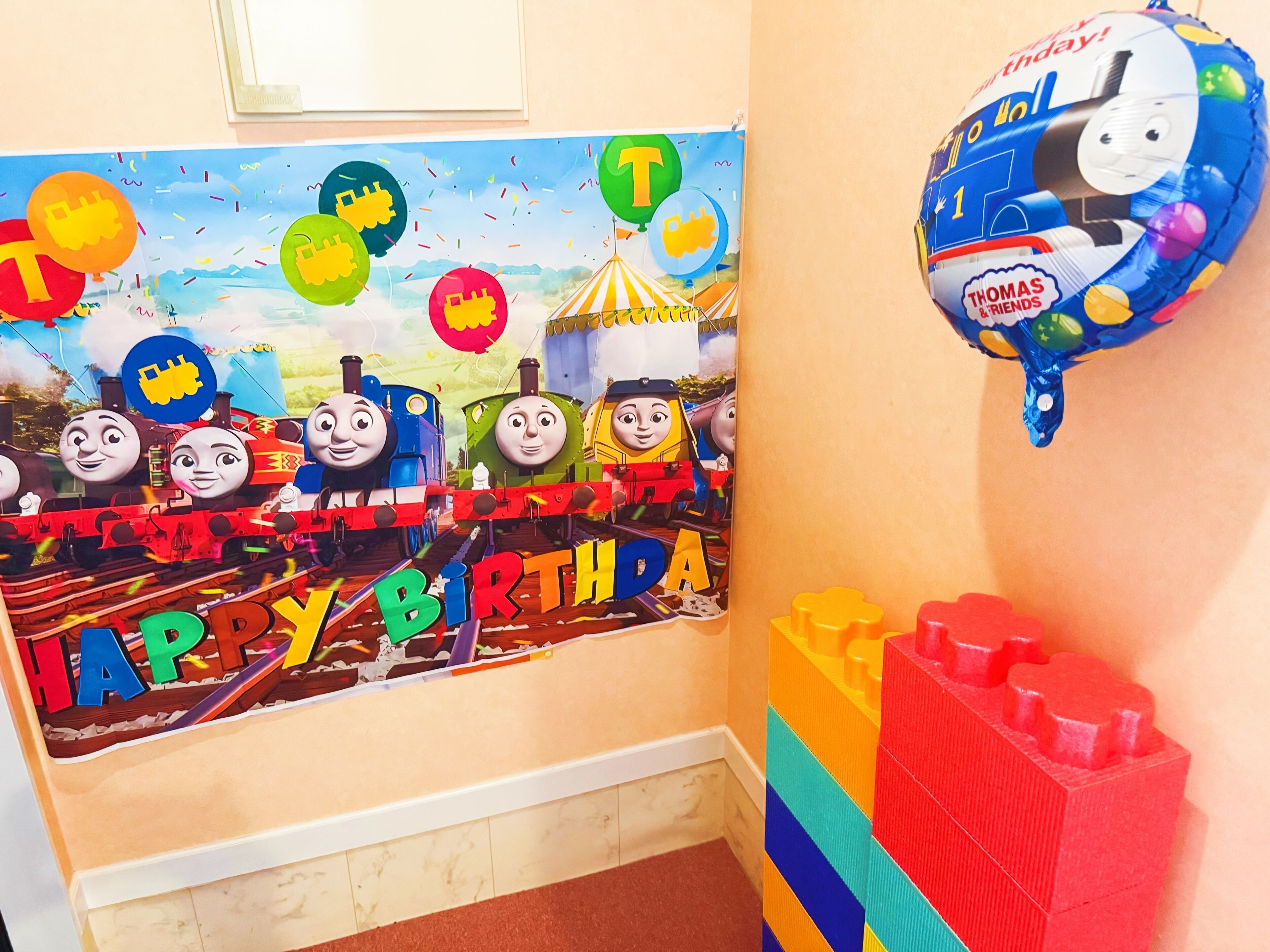A children's room decorated with Thomas the Tank Engine theme, including a wall poster and a balloon.