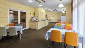 A dining area with tables and chairs, a counter with a coffee machine, and a wall with decorative items. - Ikaho no mori Kids Paradise (Yoshioka)