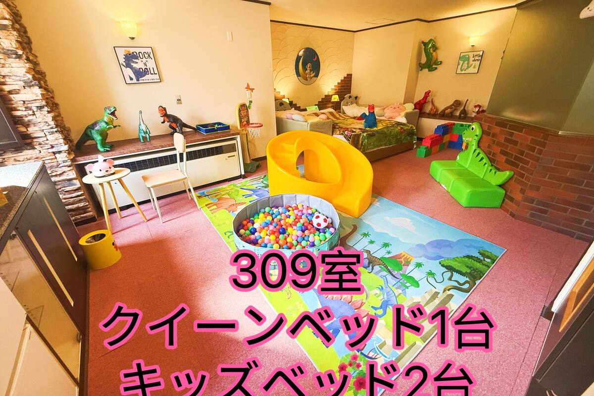A children's playroom with a ball pit, dinosaur toys, and a mural on the wall.