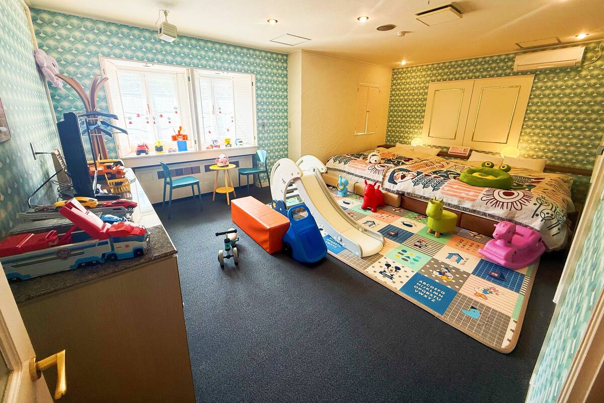 A child's playroom with a slide, toys, and a bed with a colorful quilt.