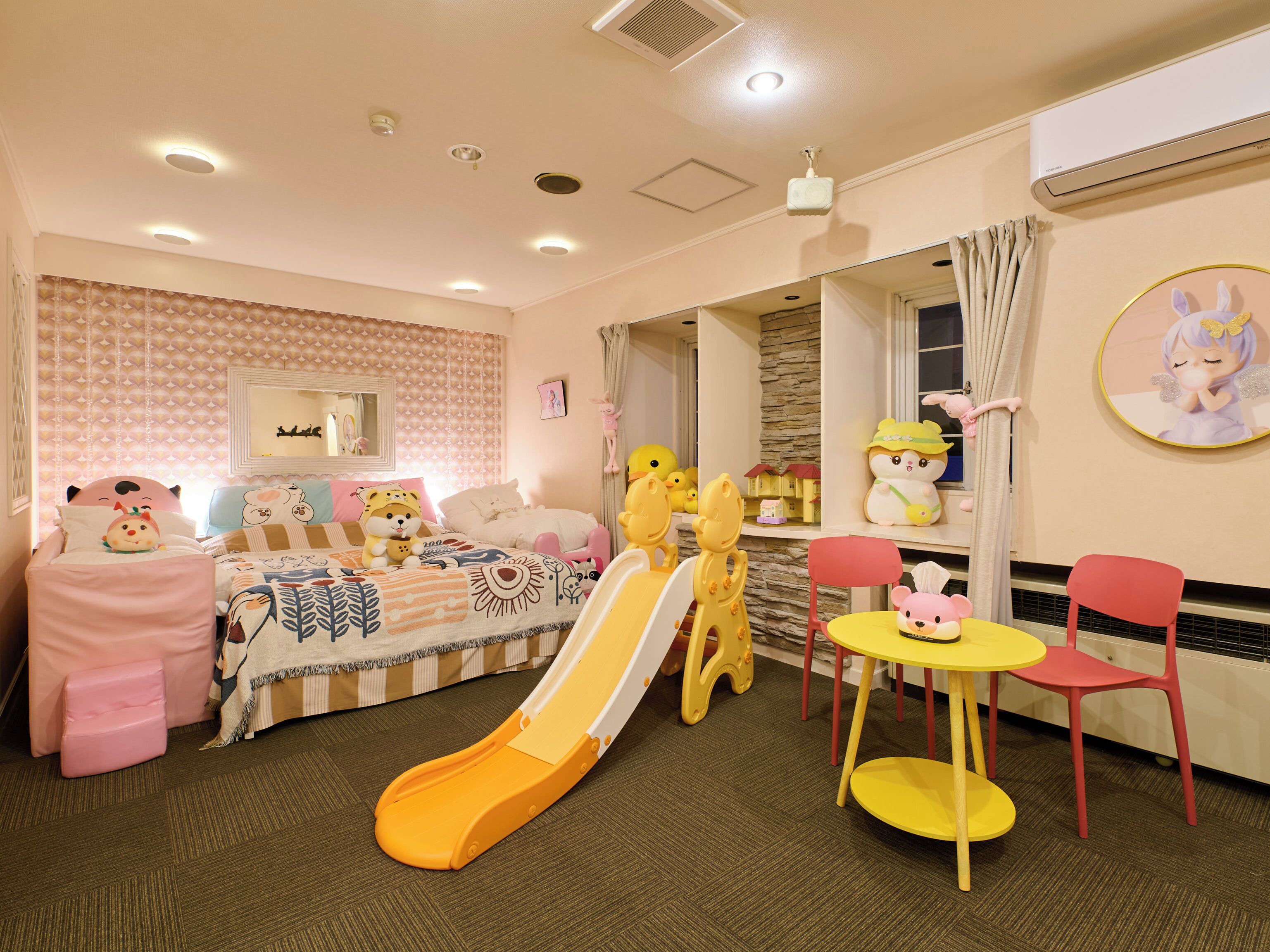 A children's playroom with a slide, play chairs, and a small table.