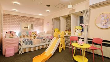 A children's playroom with a slide, play chairs, and a small table.