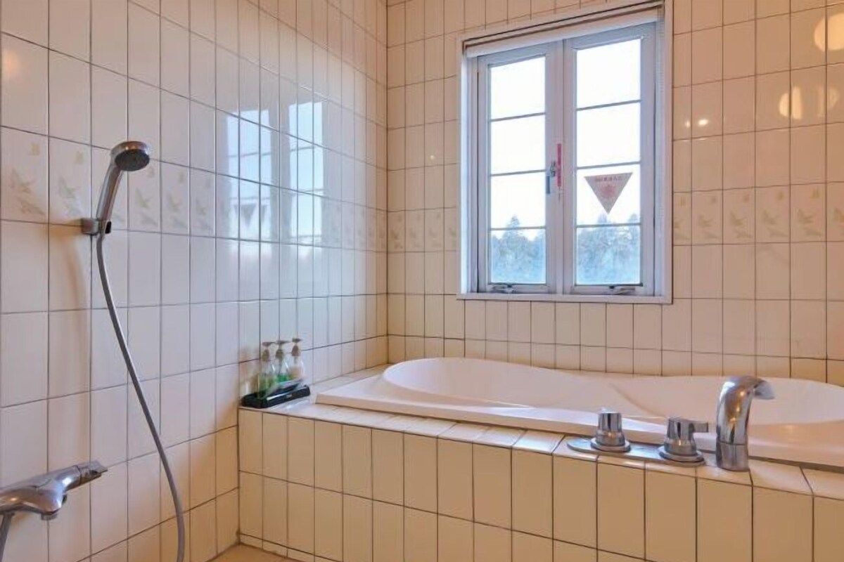 Un baño con bañera, ducha y ventana.
