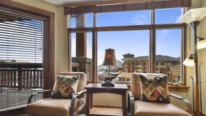 A room with two leather armchairs, a small wooden table, and a large window with a view of buildings and a dome structure.