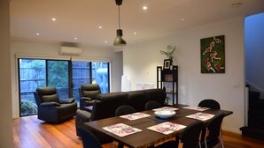 A dining area with a wooden table, black chairs, and a black sofa.