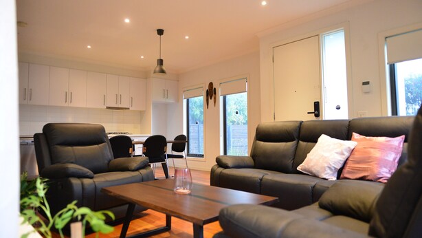 A modern living room with a sofa set, a coffee table, and a dining area with chairs.