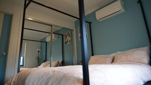 A bedroom with a four-poster bed, a ceiling fan, and an air conditioning unit.