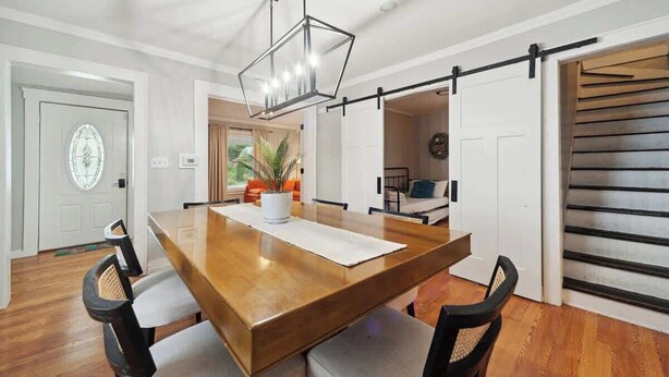 Un comedor con una mesa de madera, sillas, una lámpara colgante y una puerta corrediza de estilo rústico.
