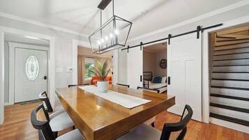 Un comedor con una mesa de madera, sillas, una lámpara colgante y una puerta corrediza de estilo rústico.