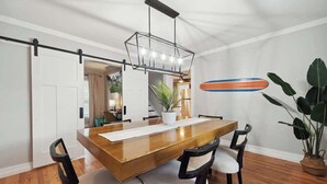 Un comedor con una mesa de madera, cuatro sillas, una lámpara colgante y una planta en maceta.