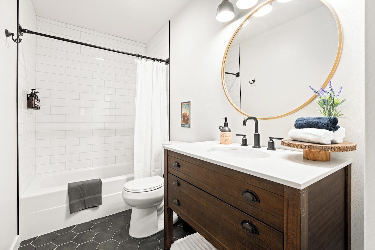 A bathroom with a bathtub, toilet, vanity with a mirror, and a shower curtain.