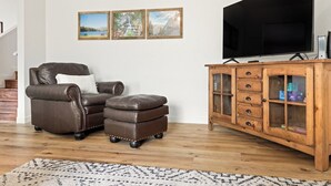 A living room with a leather sofa, ottoman, wooden cabinet, and a large flat-screen TV. - The Big Dipper between Kaweah River & Skyline, SNP (Three Rivers)