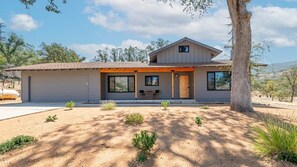 A two-story house with a garage, a covered porch, and a small garden with various plants. - The Big Dipper between Kaweah River & Skyline, SNP (Three Rivers)