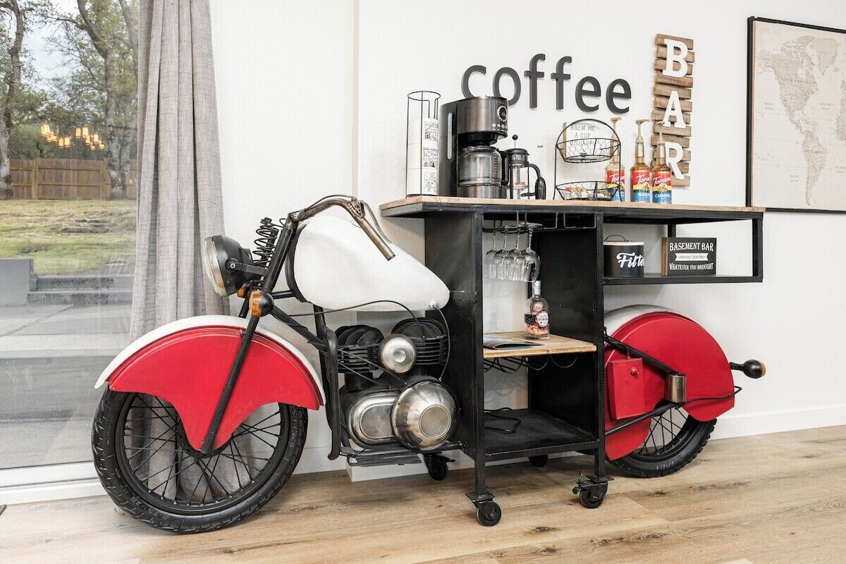 Ein altes rotes und weißes Motorrad, im Hintergrund eine Kaffeemaschine und eine Bar.