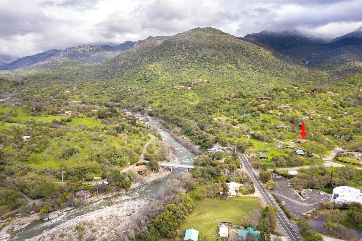 A mountainous landscape with a river, a bridge, and scattered buildings.