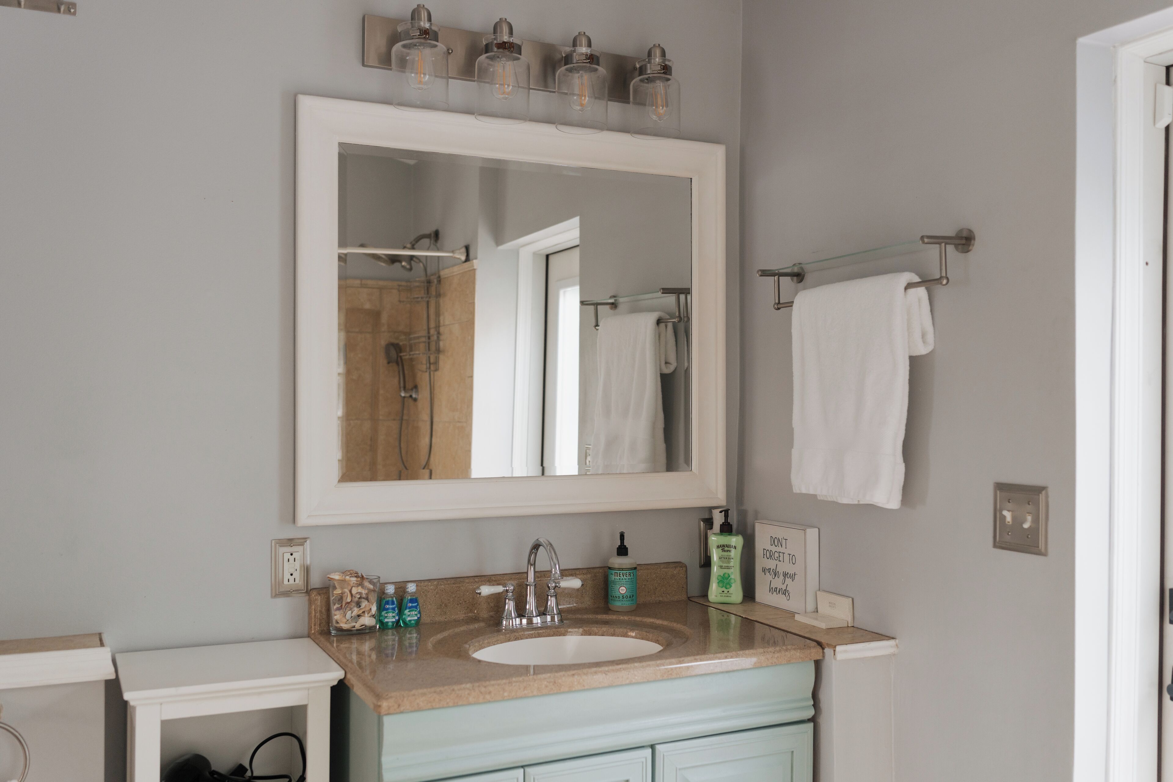Une salle de bain avec un grand miroir, un lavabo et un porte-serviettes.