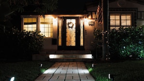 A house with a well-lit front door, a mailbox, and a number sign.