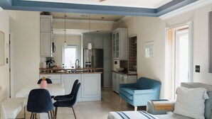 A modern kitchen with white cabinets, a central island, and a dining area with a white table and black chairs.