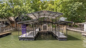 Een overdekte steiger met een klein tuinhuisje, omgeven door water en bomen.