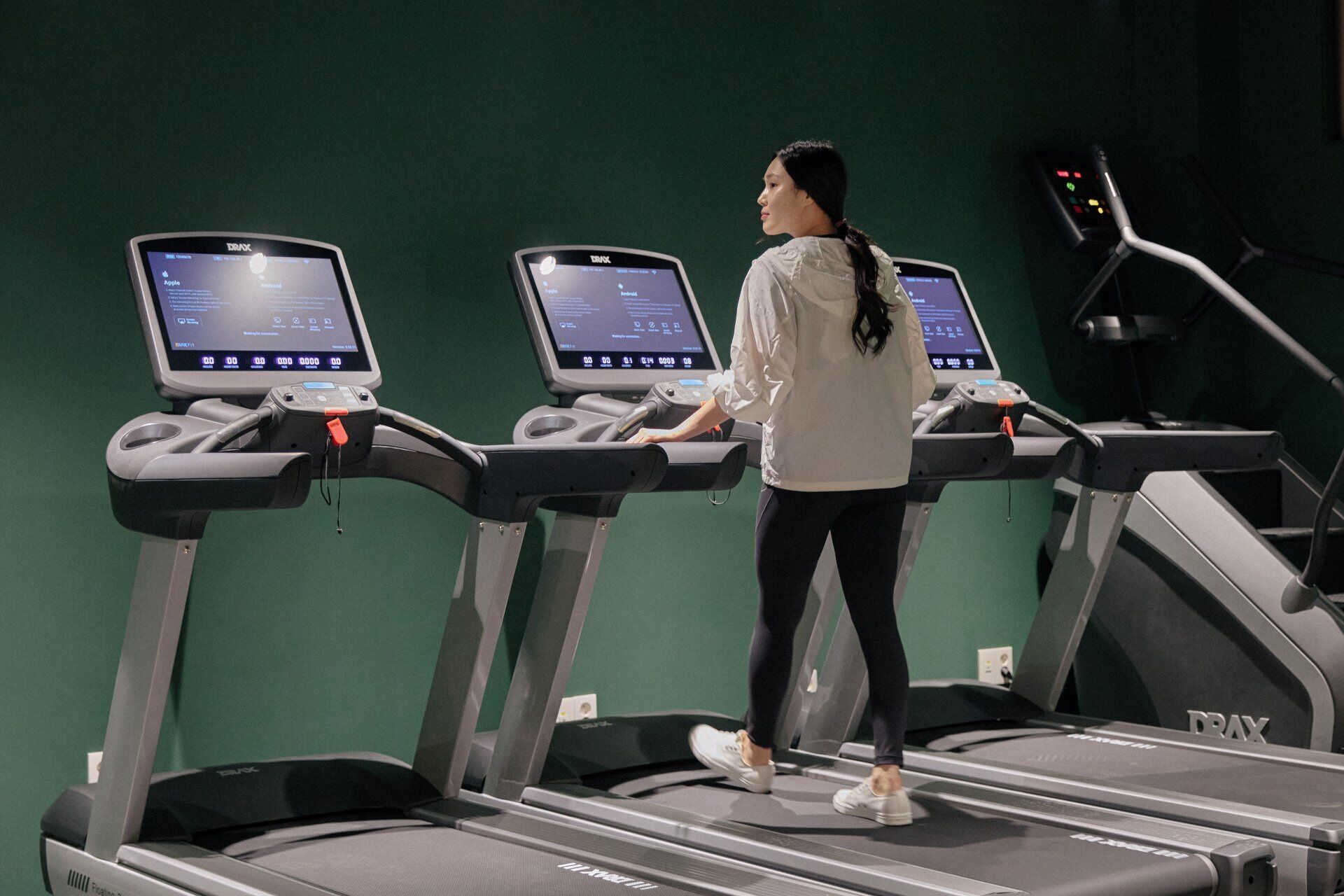 Una persona usando una cinta de correr con pantallas digitales.