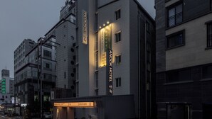 Un hotel moderno con señalización iluminada, un acceso cubierto y una planta baja visible con recepción.