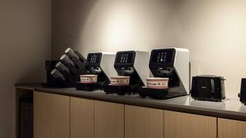 A row of coffee machines with disposable cups on a counter.