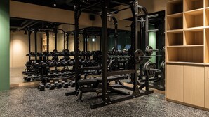 Un gimnasio con equipo de levantamiento de pesas, cintas de correr y un espejo grande.