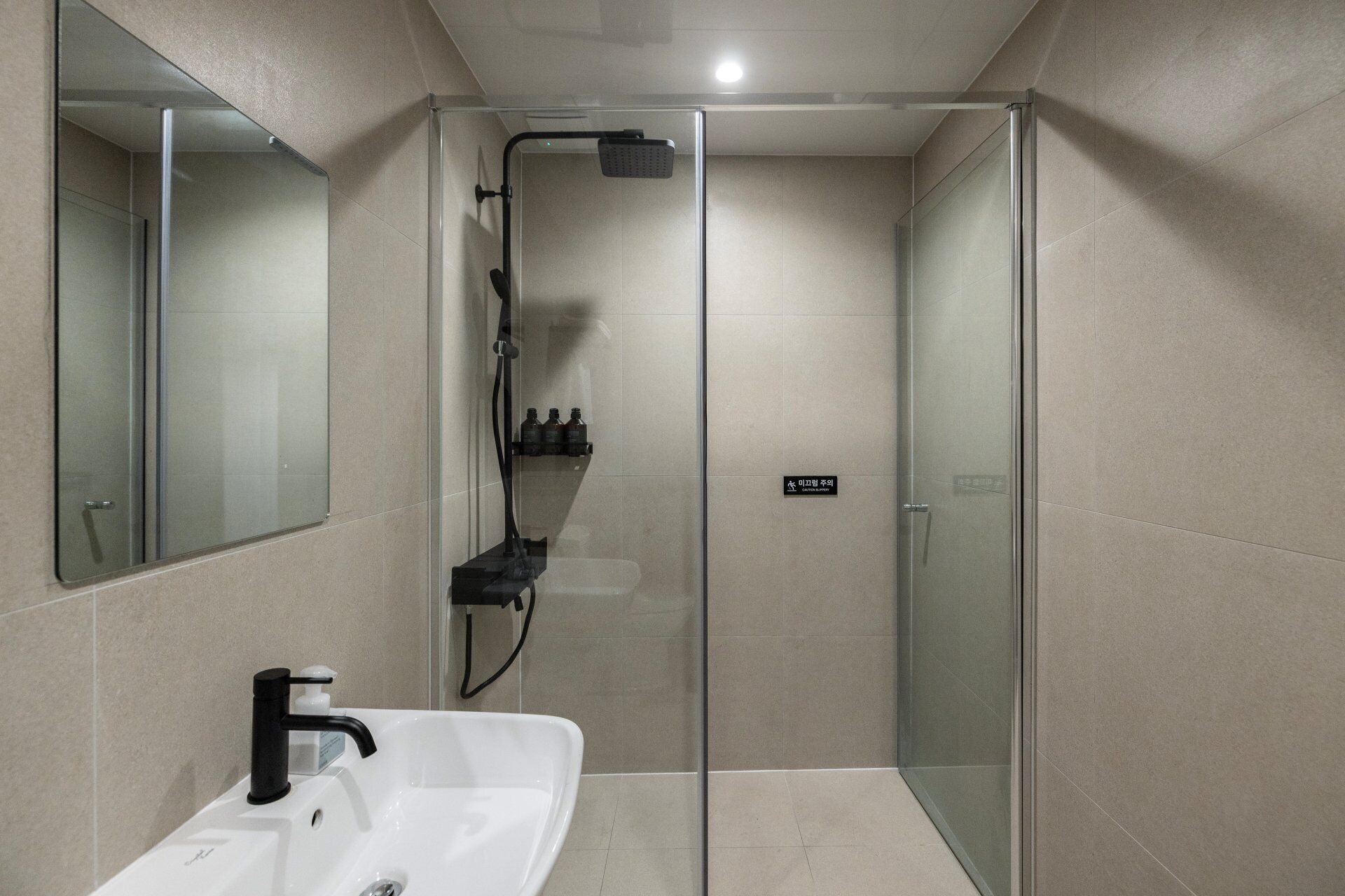 Un baño moderno con cabina de ducha de vidrio, un lavabo blanco y un espejo.