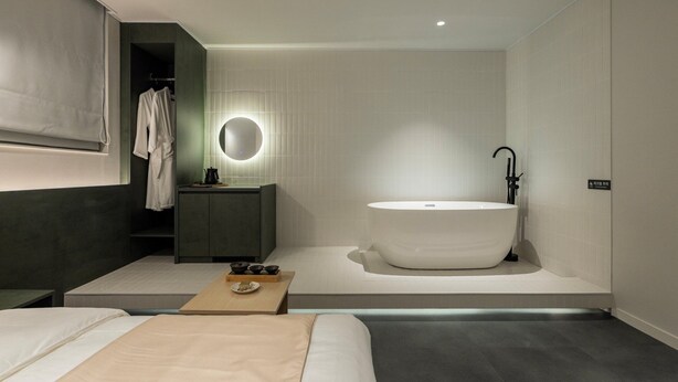 Un baño moderno con una bañera independiente, un espejo redondo y un tocador minimalista.