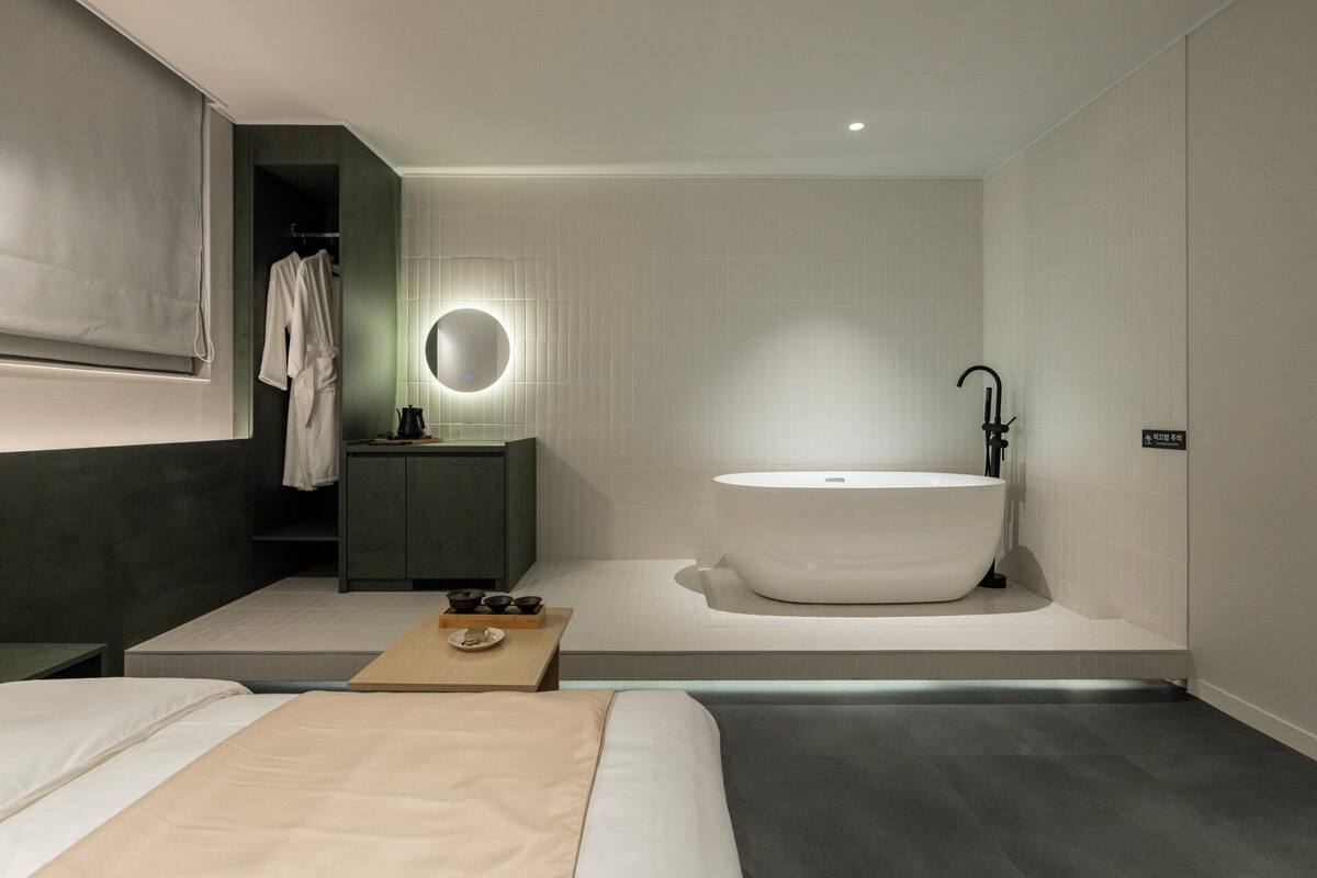 Une salle de bain moderne avec une baignoire sur pieds, un miroir rond et un meuble-lavabo au design épuré.