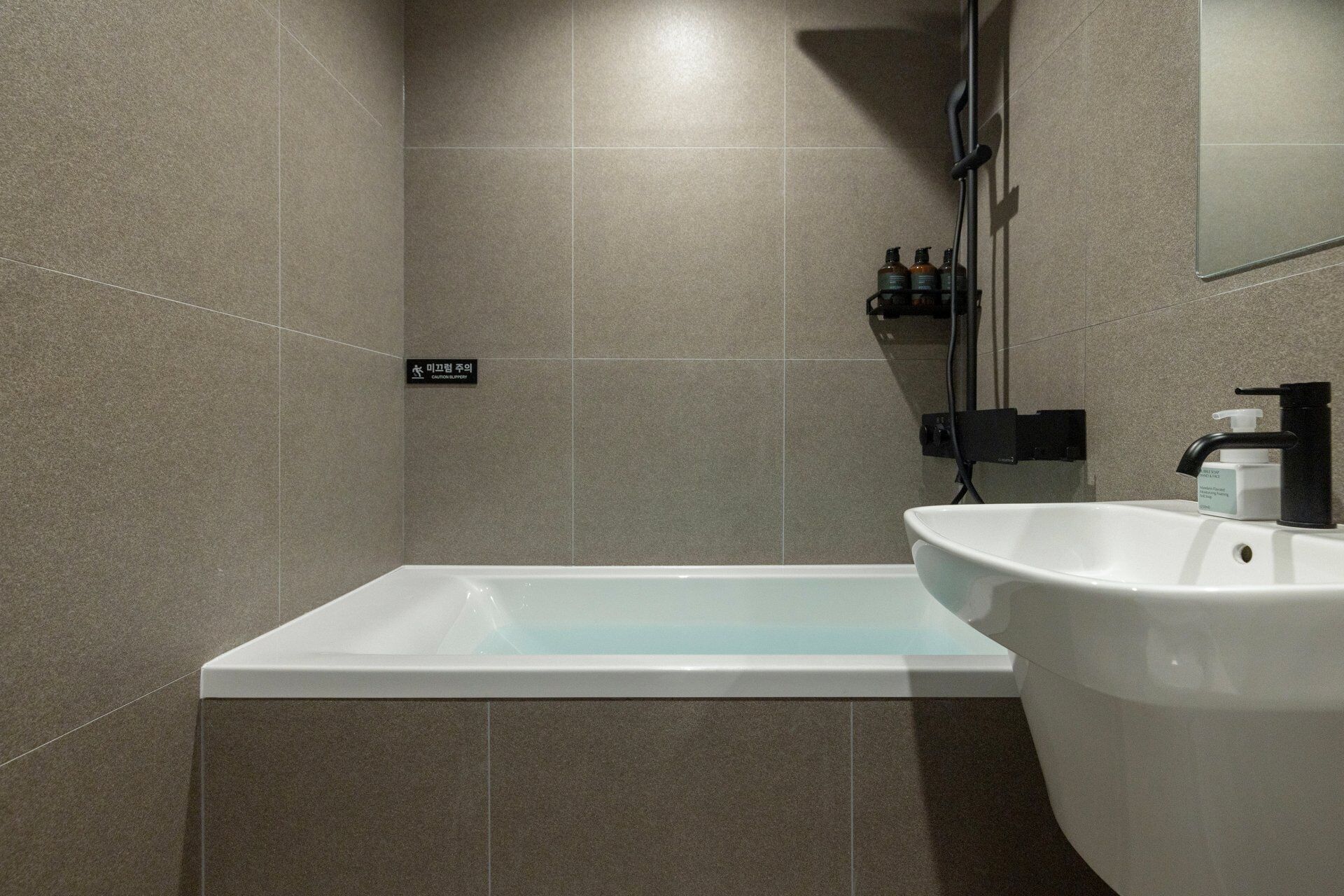 A modern bathroom with a rectangular bathtub, a white sink, and a mirror.
