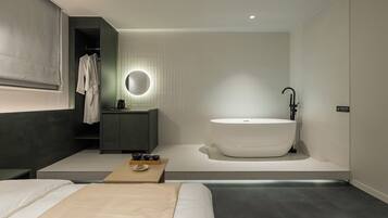 Une salle de bain moderne avec une baignoire sur pieds, un meuble-lavabo avec un miroir et un porte-serviettes.