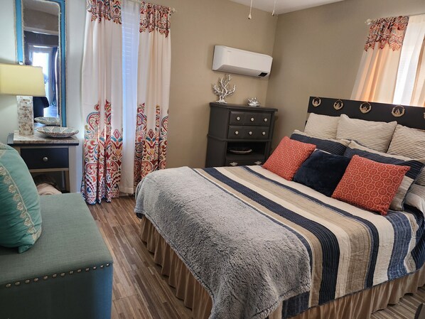 A neatly arranged bedroom with a bed, bedside table, dresser, and a mirror. - Lil Beachy (Memphis)