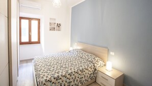 A bedroom with a bed, bedside lamps, a window, and wall art.