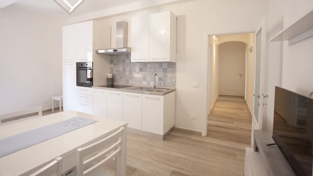 A modern kitchen with white cabinets, a built-in oven, and a tiled backsplash.