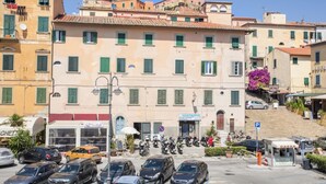 A street view with a row of buildings, a parked car, and a sign for a physiotherapy clinic.