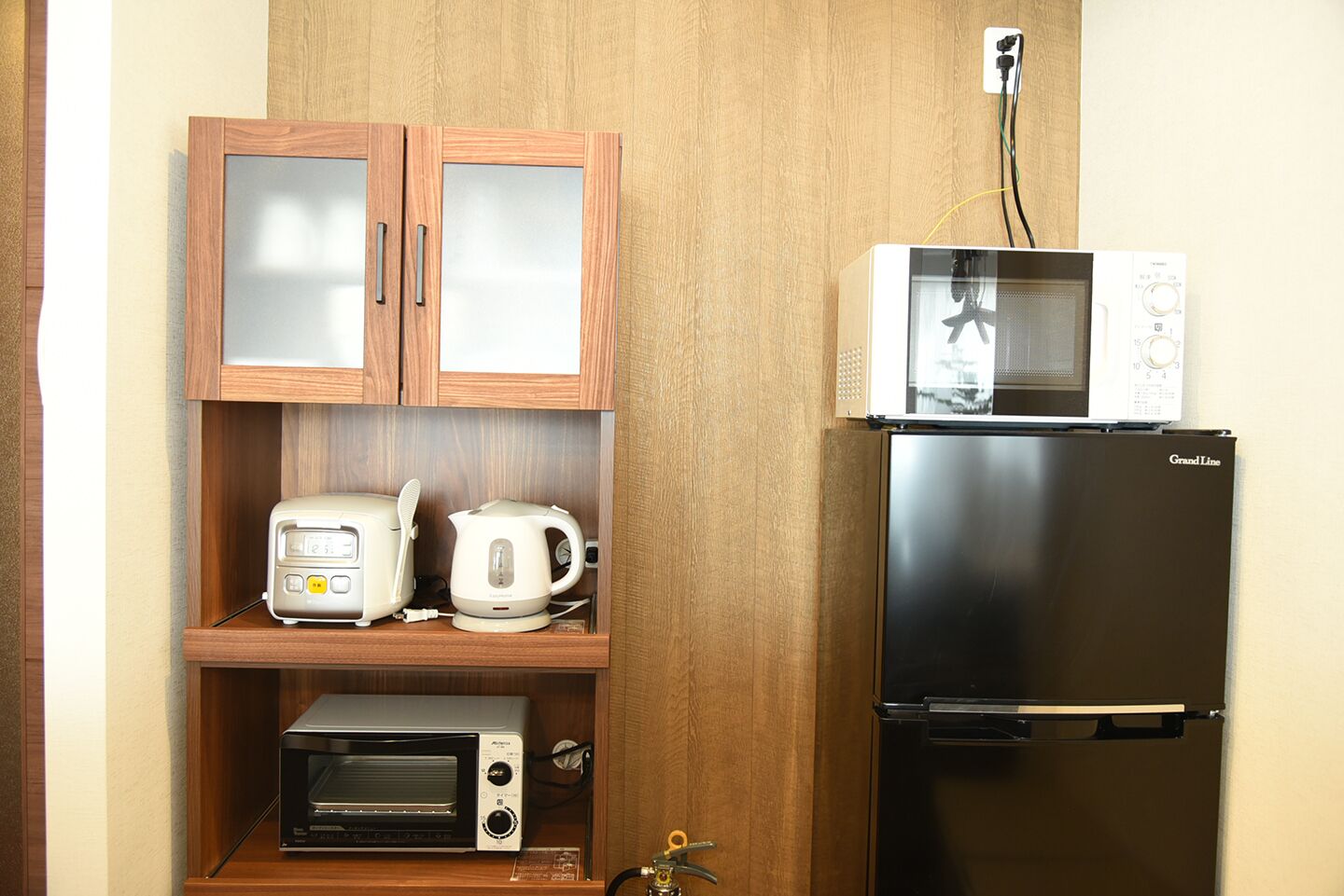A compact kitchenette with a microwave, toaster, kettle, and a small oven.