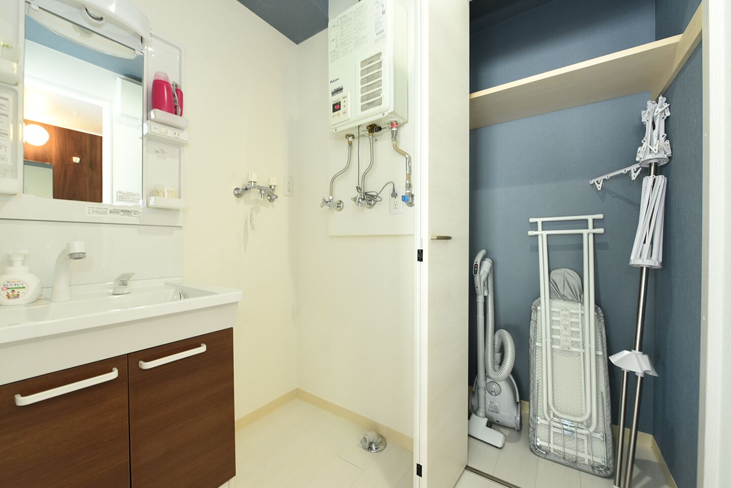 Een moderne badkamer met een witte wastafel, houten kastjes, een spiegel, een douche met een handdouche en een handdoekrek.