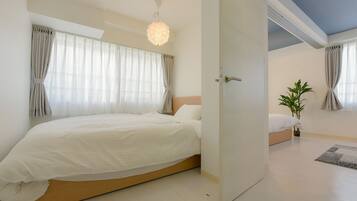 Une chambre à coucher moderne avec un grand lit, une table de chevet, un luminaire suspendu et une plante en pot.