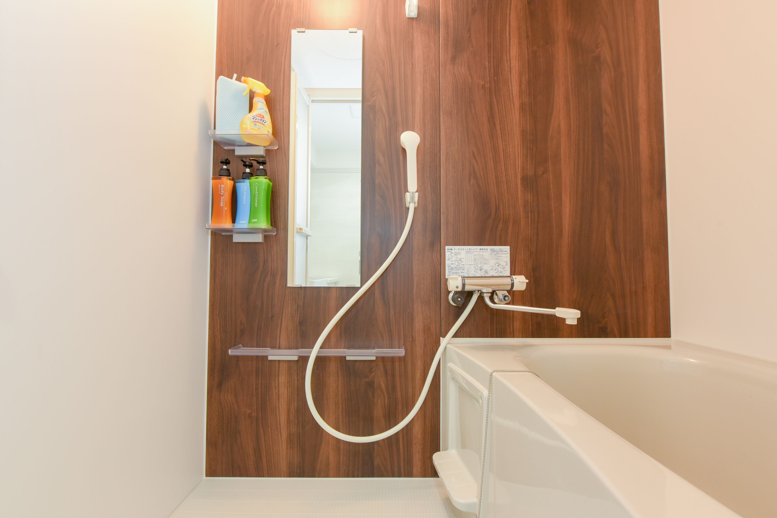 Ein Badezimmer mit Holzwand, einer weißen Badewanne und einer Dusche mit Duschbrause.