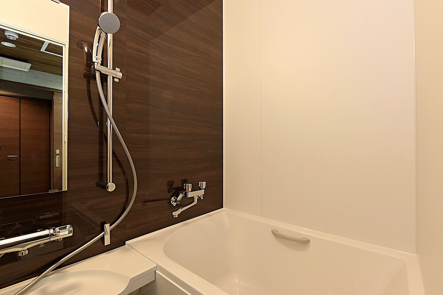 A modern bathroom with a bathtub, a shower with a handheld showerhead, and a vanity with a mirror.