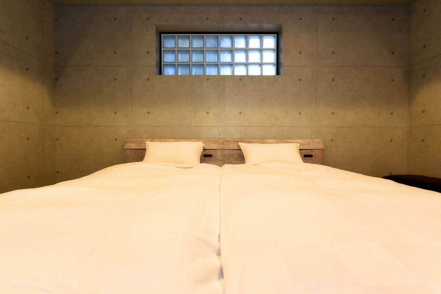 A double bed with a wooden headboard and a window above it.