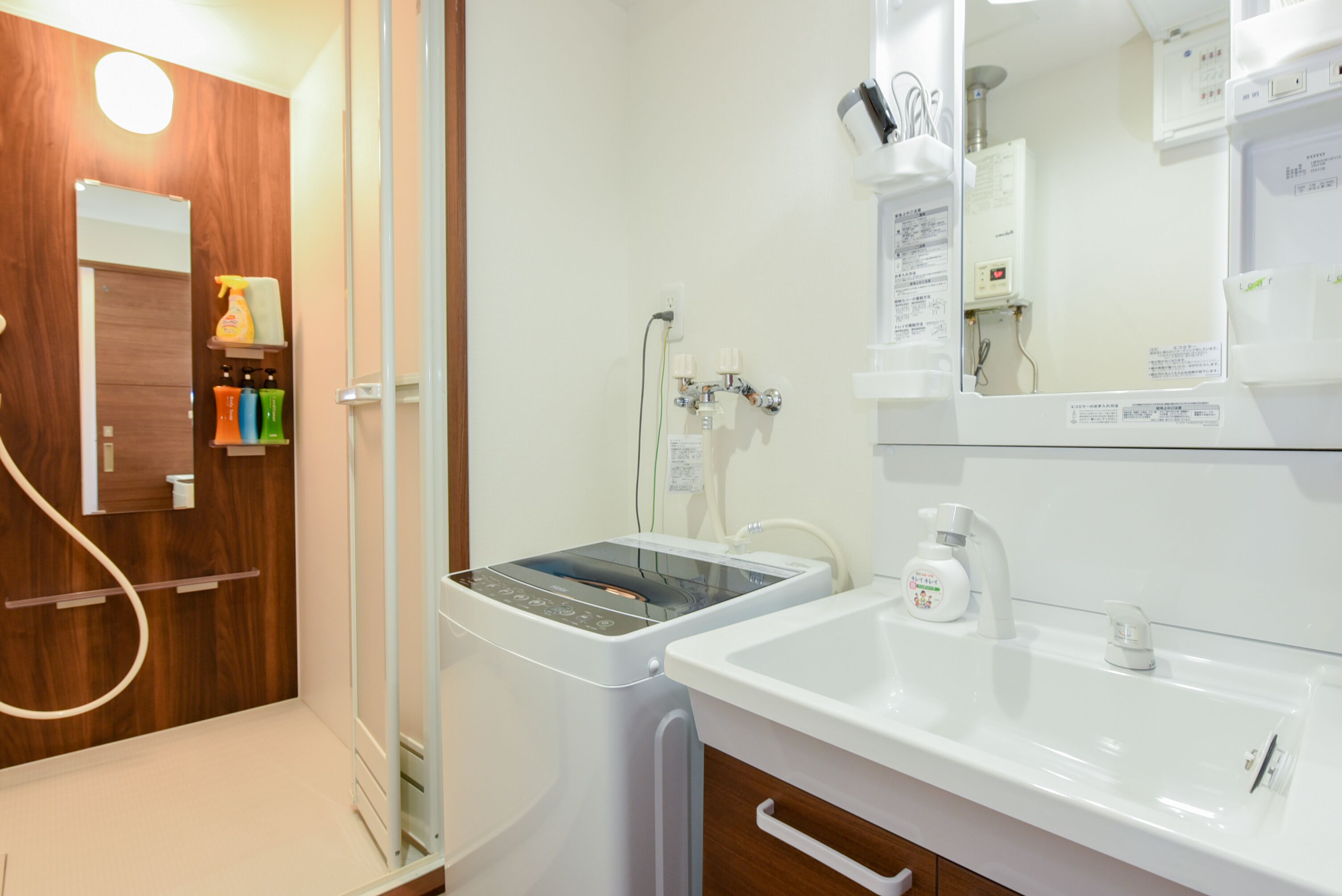 A modern bathroom with a built-in washing machine, a sink, and a mirror.