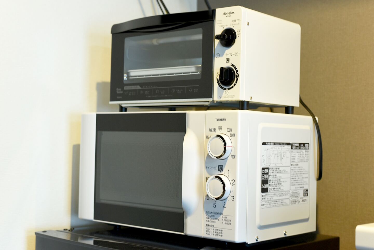 Deux fours à micro-ondes superposés, posés sur un support noir.