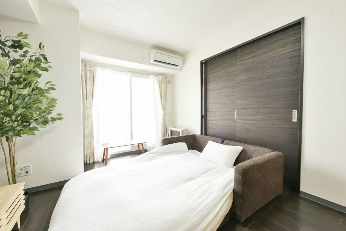 Ein modernes Hotelzimmer mit Bett, Sofa, großem Fenster und Klimaanlage.