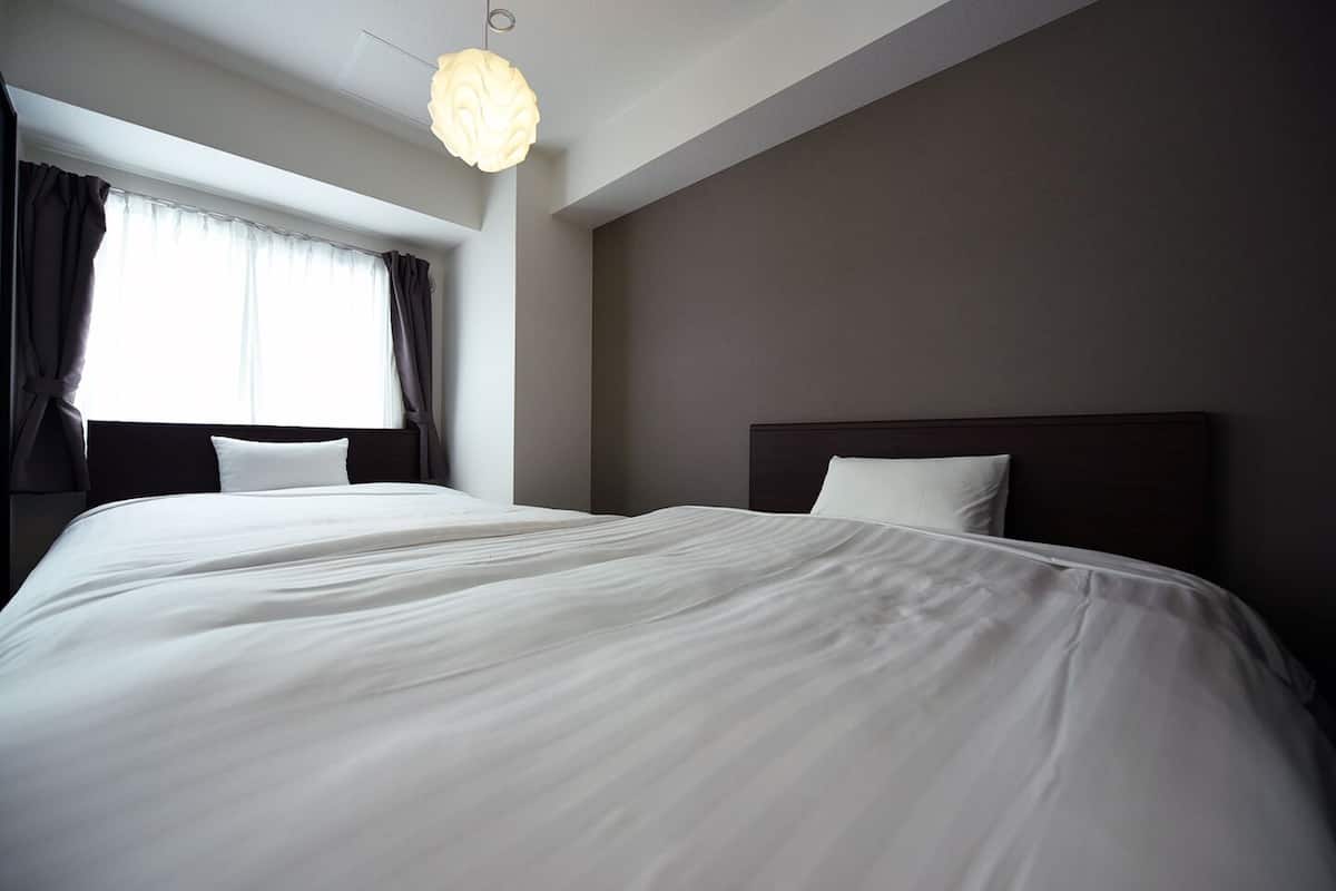 Una habitación de hotel con una cama grande, cabecera oscura y una lámpara colgante.