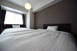 Una habitación de hotel con una cama grande, cabecera oscura y una lámpara colgante.