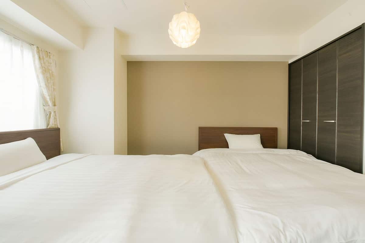 Habitación de hotel con dos camas, un armario grande y una lámpara colgante.