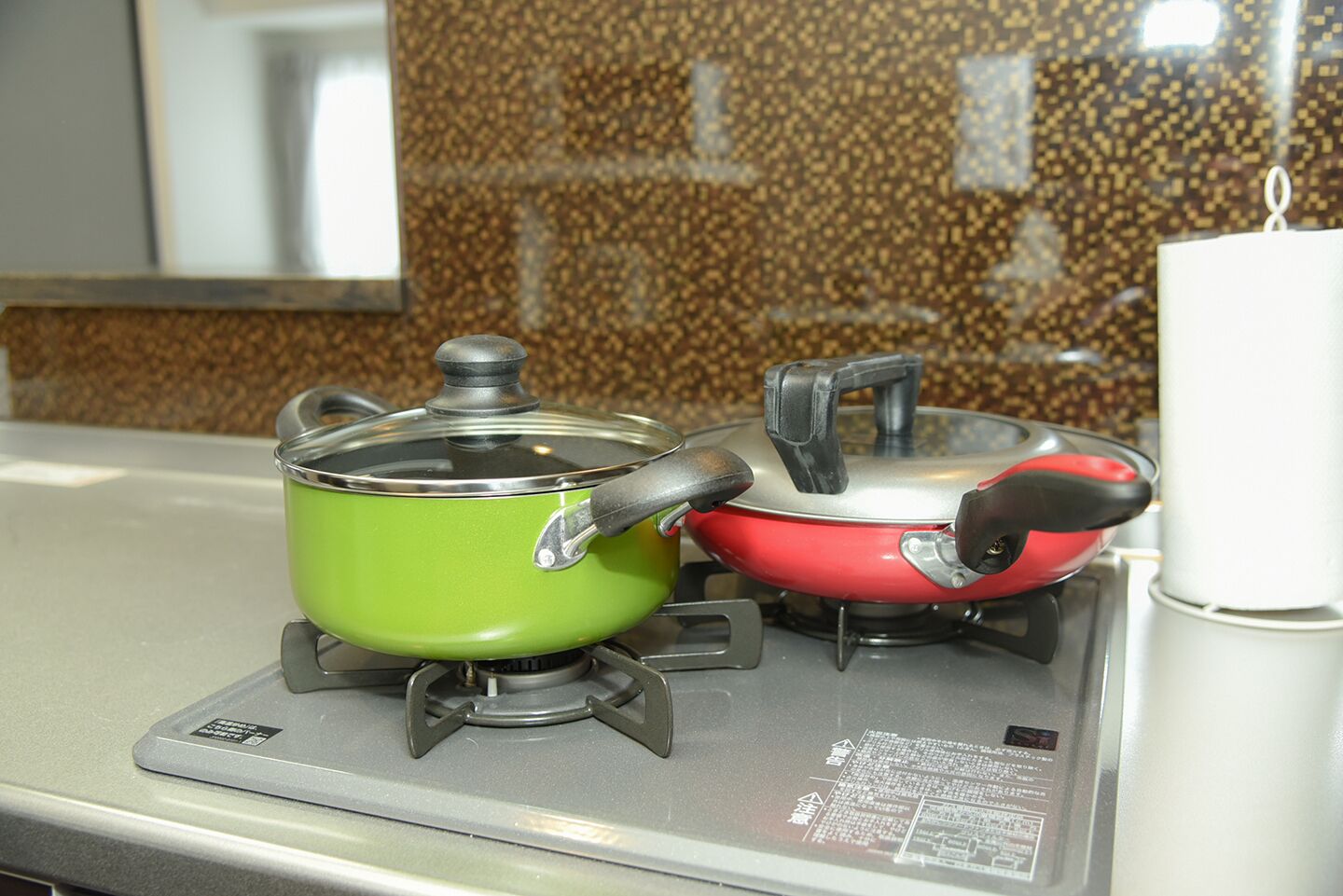 Two pots on a gas stove with a granite backsplash.